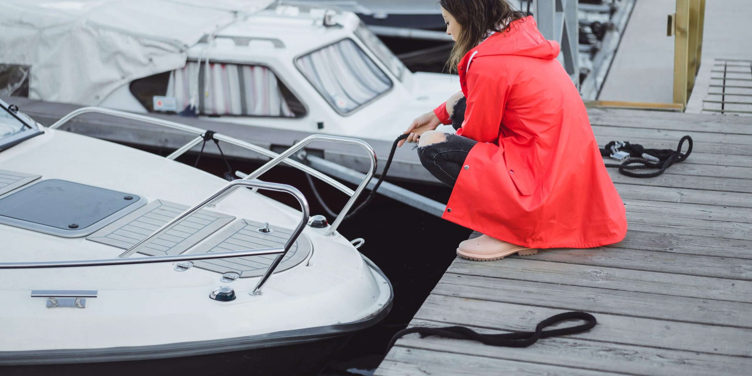 Beautiful young woman in a red cloak in the yacht port. Stockhol