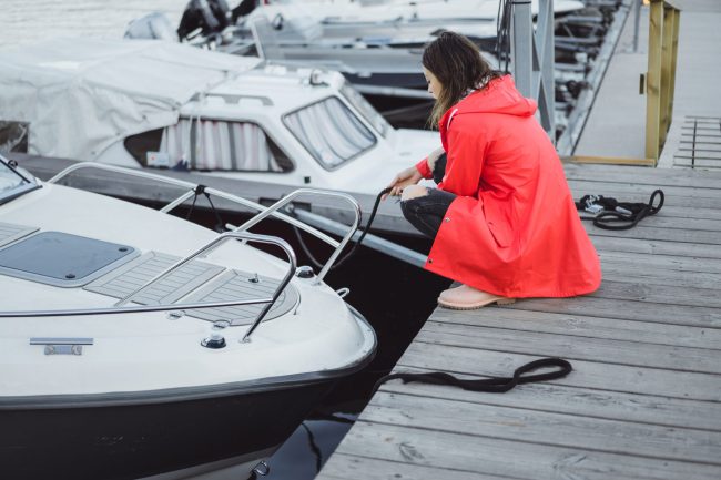 Beautiful young woman in a red cloak in the yacht port. Stockhol